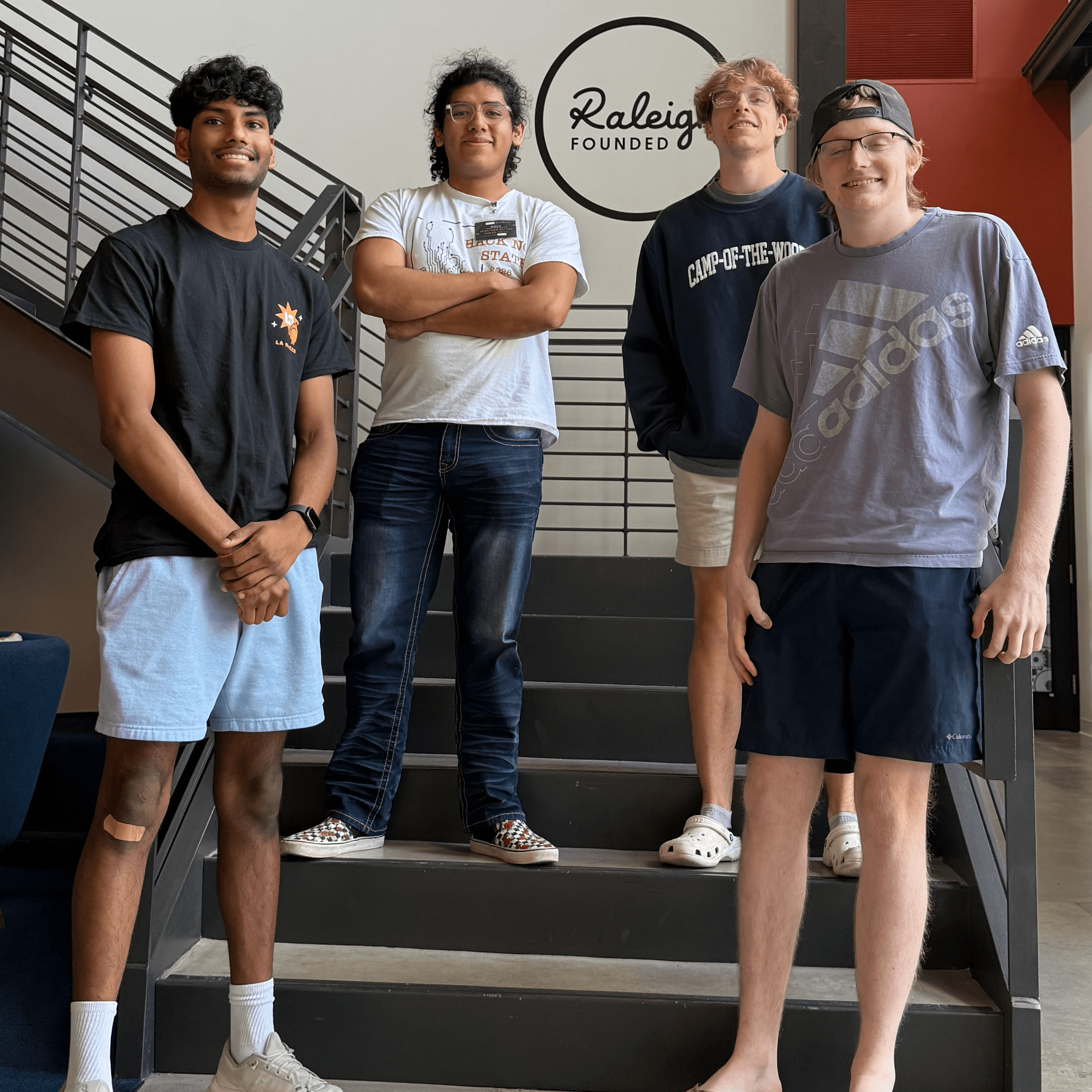 Five members of the Thinking Machines club gathered on a staircase in the NC State Entrepreneurship Garage